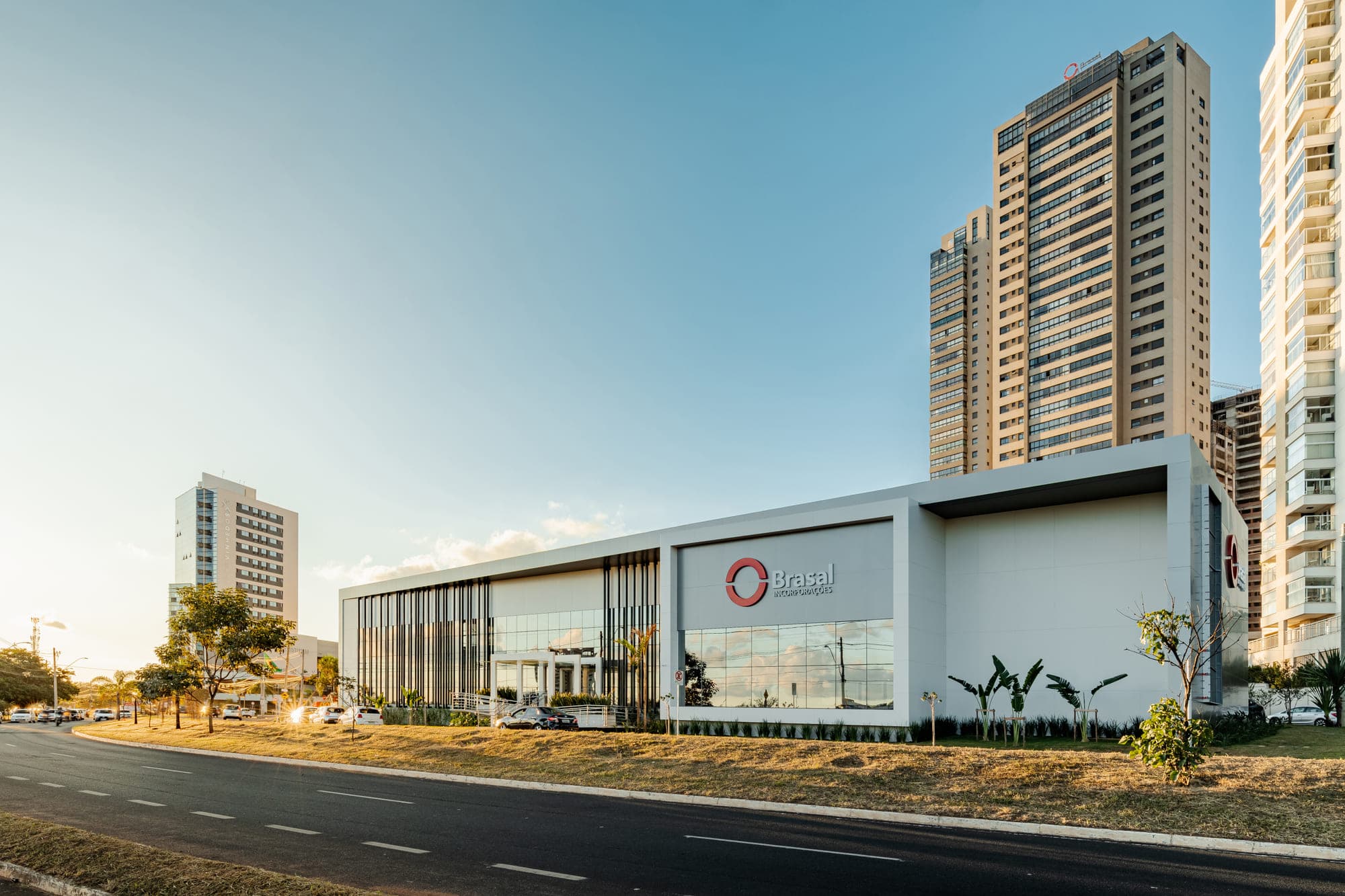 O mesmo edifício comercial visto da avenida, com a fachada de brises brancos ao longo da via
