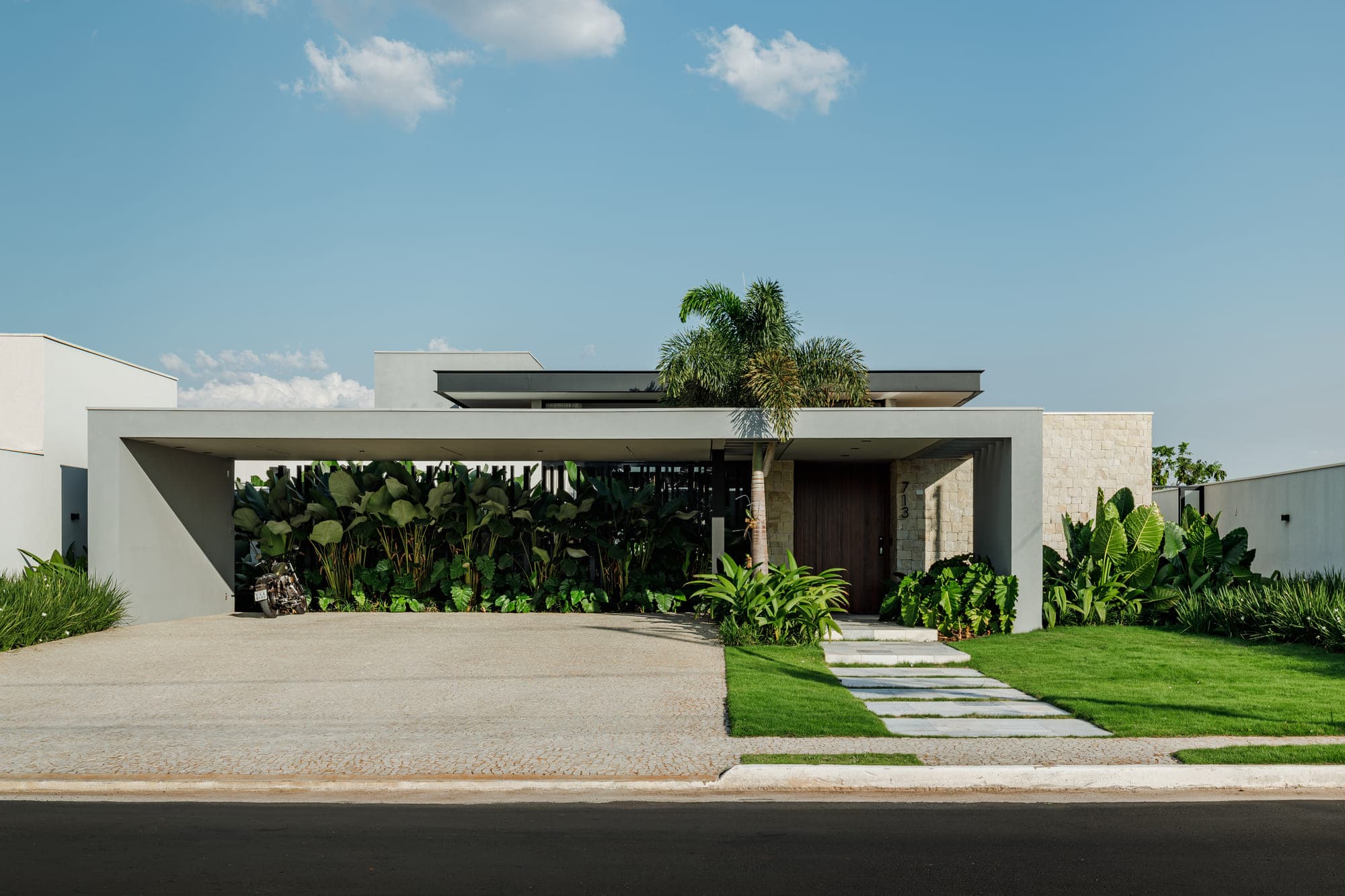 Casa com marquise em concreto e palmeira no eixo da fachada, fotografada de frente